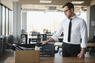 Genç yakışıklı işadamı karton kutu ışık modern ofiste. Son günün. Üzgün ofis çalışanı işten
