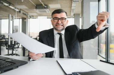 Kızgın işadamı masada oturup bağırıyor.