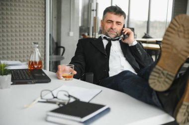 Yaşlı işadamı ofiste içki içiyor..