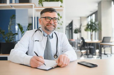 Gözlüklü ve beyaz önlüklü ciddi bir kıdemli doktorun portresi.