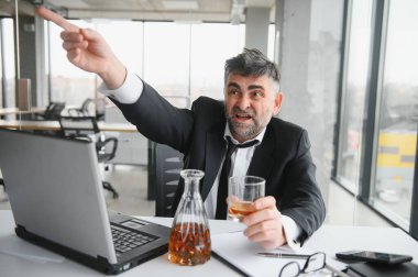 Alcoholism at work. Tired employee drinking alcohol at workplace, can not handle stress.