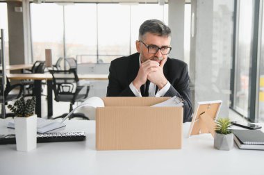 Ofis malzemelerini kutuya koyan üzgün yaşlı işadamı portresi. Emekliler işten emekli olur, çalışanları eve taşır. Yaşam tarzı iş emekliliği, iş bırakma kavramı.