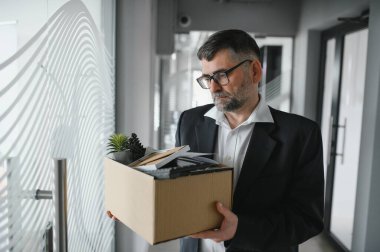 Ofis malzemelerini kutuya koyan üzgün yaşlı işadamı portresi. Emekliler işten emekli olur, çalışanları eve taşır. Yaşam tarzı iş emekliliği, iş bırakma kavramı.