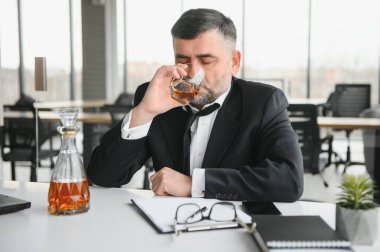 Alcoholism at work. Tired employee drinking alcohol at workplace, can not handle stress.