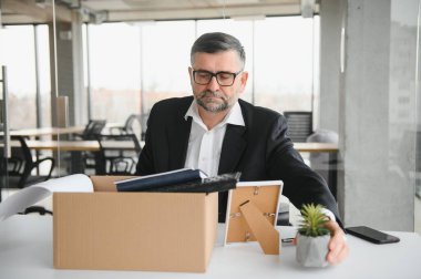 Ofis malzemelerini kutuya koyan üzgün yaşlı işadamı portresi. Emekliler işten emekli olur, çalışanları eve taşır. Yaşam tarzı iş emekliliği, iş bırakma kavramı.
