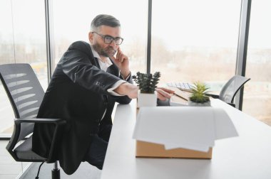 Ofis malzemelerini kutuya koyan üzgün yaşlı işadamı portresi. Emekliler işten emekli olur, çalışanları eve taşır. Yaşam tarzı iş emekliliği, iş bırakma kavramı.