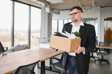 Ofis malzemelerini kutuya koyan üzgün yaşlı işadamı portresi. Emekliler işten emekli olur, çalışanları eve taşır. Yaşam tarzı iş emekliliği, iş bırakma kavramı.