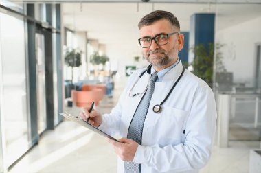 Gözlüklü ve beyaz önlüklü ciddi bir kıdemli doktorun portresi.