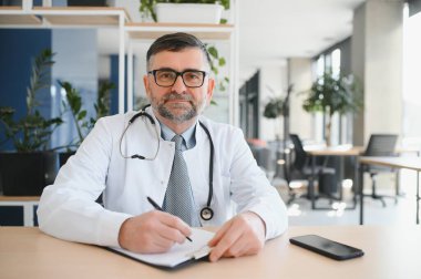 Gözlüklü ve beyaz önlüklü ciddi bir kıdemli doktorun portresi.