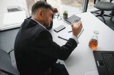 Yaşlı işadamı ofiste içki içiyor..