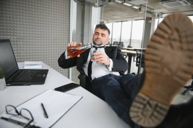 Alcoholism at work. Tired employee drinking alcohol at workplace, can not handle stress.