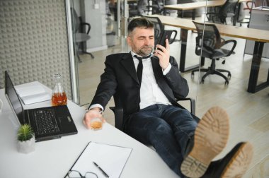 Alcoholism at work. Tired employee drinking alcohol at workplace, can not handle stress.