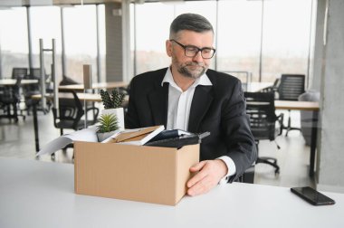 Ofis malzemelerini kutuya koyan üzgün yaşlı işadamı portresi. Emekliler işten emekli olur, çalışanları eve taşır. Yaşam tarzı iş emekliliği, iş bırakma kavramı.