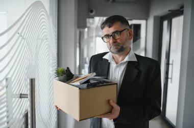 Ofis malzemelerini kutuya koyan üzgün yaşlı işadamı portresi. Emekliler işten emekli olur, çalışanları eve taşır. Yaşam tarzı iş emekliliği, iş bırakma kavramı.