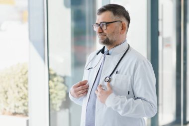 Gri saç uzmanlığı yakışıklı yaşlı doktor hastane portresi.