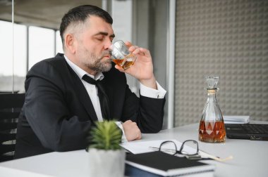 Alcoholism at work. Tired employee drinking alcohol at workplace, can not handle stress.