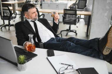 Yaşlı işadamı ofiste içki içiyor..