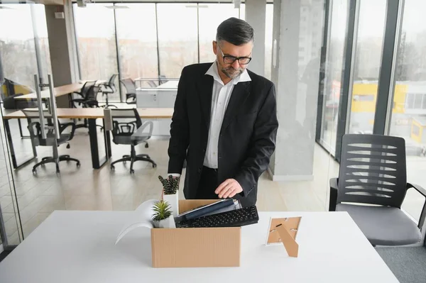 Portrait of sad dismissed senior old business man worker taking his office supplies in the box. Pensioner mature retire from work carry staff back home. Lifestyle business retirement, quit job concept.