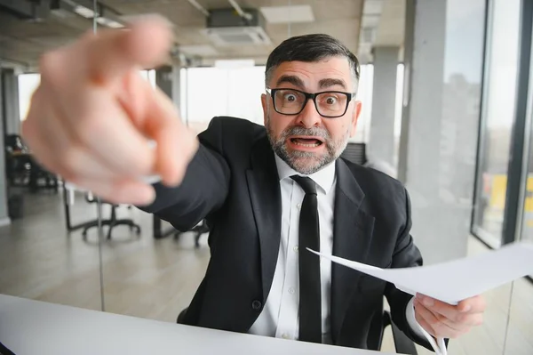 Angry businessman with document shouting at somebody.