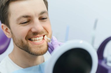 Kontrol ve genç adamın dişlerini rengi seçerek diş hekimi