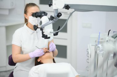 Diş sağlığı muayenehanesinde diş mikroskobu kullanan kadın diş hekimi..