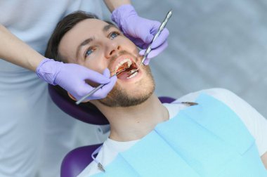 Diş bakımı konsepti. Dişçinin ofisindeki yakışıklı genç adam.