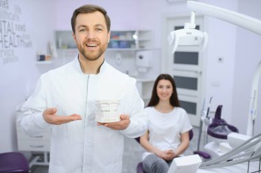 Diş Merkezi. Gülümseyen Orta Doğulu dişçi doktor pozu, yakışıklı Arap stomatolojist modern klinik içinde duruyor,.