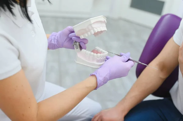 Woman dental doctor. dentist shows model of Jaws. Visual aid for training orthodontists. Sample Jaws for teaching dentists. Blurred woman dentist teaches to look after teeth. Dental health