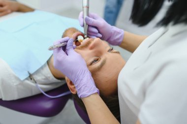 Diş bakımı konsepti. Dişçinin ofisindeki yakışıklı genç adam.