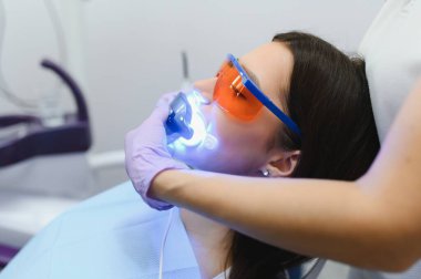 Kız hastada diş Kliniği. UV lambası fotopolimer bileşimi ile diş beyazlatma