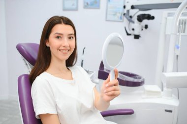Dişçi dolabındaki güzel kız bir doktorun ideal çalışmalarına bakmak için ayna kullanıyor.