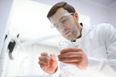 Alt manzara. Elinde bir aletle dişçi.