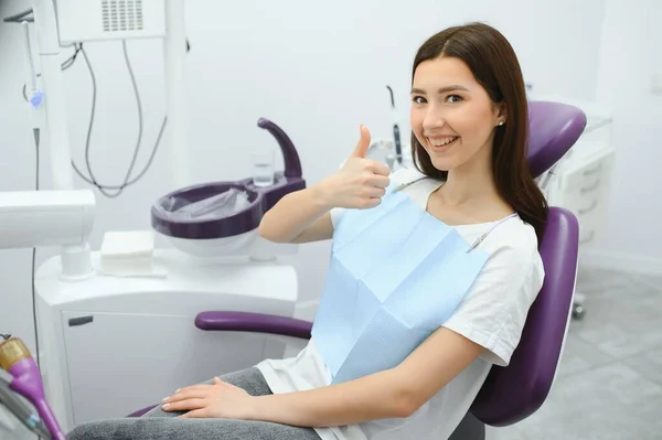 坐在牙科办公室牙科椅上一位带着牙齿微笑的女人的肖像 — 图库照片
