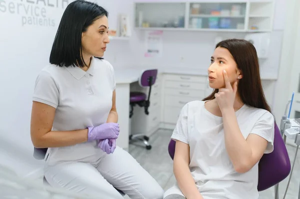 医療センターで歯科椅子に座っているかなり若い女性の画像一方 専門医彼女の歯を固定 — ストック写真
