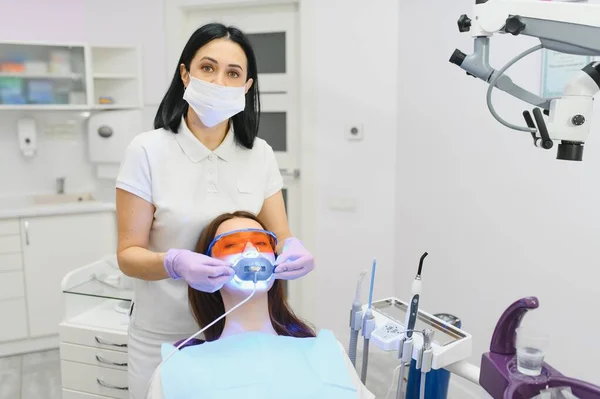 Girl patient in the dental clinic. Teeth whitening UV lamp with photopolymer composition
