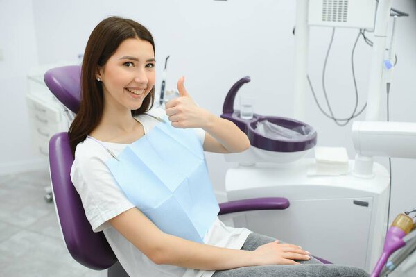 The girl is at the reception at the dentist. A happy client at the dentist smiles. . Dental bleaching. Dental clinic. Treatment of teeth in a modern clinic. Restoration of a healthy smile. Successful.