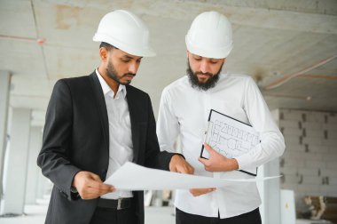 Çok ırklı iş adamları. İnşaat konsepti. Hint ve Arap mühendisler inşaatı denetliyor.