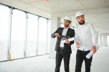 İnşaat alanındaki projeyi tartışan çok ırklı erkek çalışanlar..