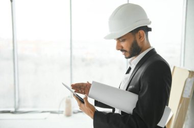 Hintli şantiye müdürü miğfer takıyor, inşaat alanında düşünüyor. Karışık ırk el işçisinin ya da mimarın portresi
