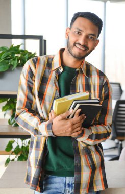 Üniversitede sırt çantası ve kitapları olan yakışıklı bir Hintli çocuk. Eğitim kavramı.