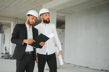 İnşaat alanındaki projeyi tartışan çok ırklı erkek çalışanlar..