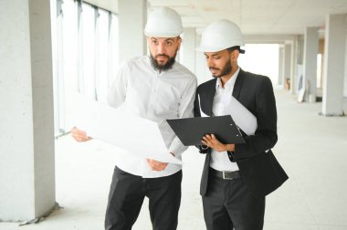 Çok ırklı iş adamları. İnşaat konsepti. Hint ve Arap mühendisler inşaatı denetliyor.