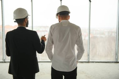 İnşaat alanındaki projeyi tartışan çok ırklı erkek çalışanlar..