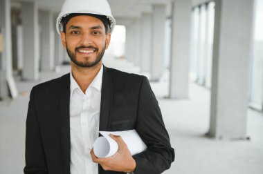 İnşaat alanında beyaz kasklı Asyalı mühendis ya da mimar. Modern bina inşaatında duruyor. Asyalı işçi proje inşaatında çalışıyor..