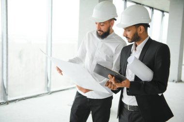 Çok ırklı iş adamları. İnşaat konsepti. Hint ve Arap mühendisler inşaatı denetliyor.