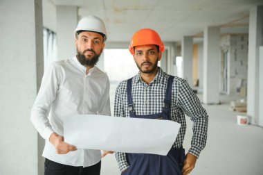 İnşaat alanındaki projeyi tartışan çok ırklı erkek çalışanlar..