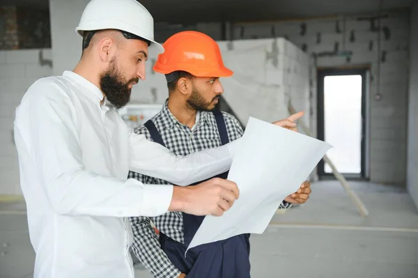 多个种族的男同事戴着硬帽讨论建筑工地的工程 — 图库照片
