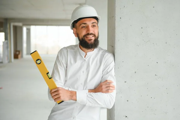 Young attractive arabic industrial engineer in hard hat. Professional and industry, builder architect job, worker checking work at plant indoor.
