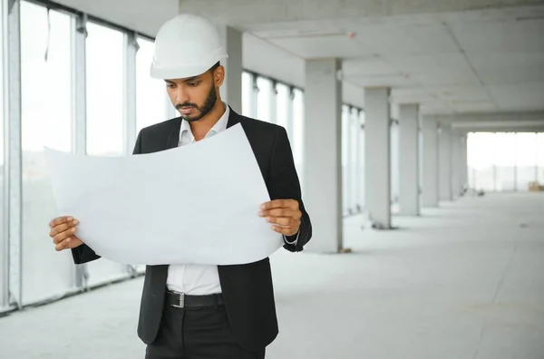 Asian engineer handsome man or architect with white safety helmet in construction site. Standing at modern building construction. Worker asian man working project building.