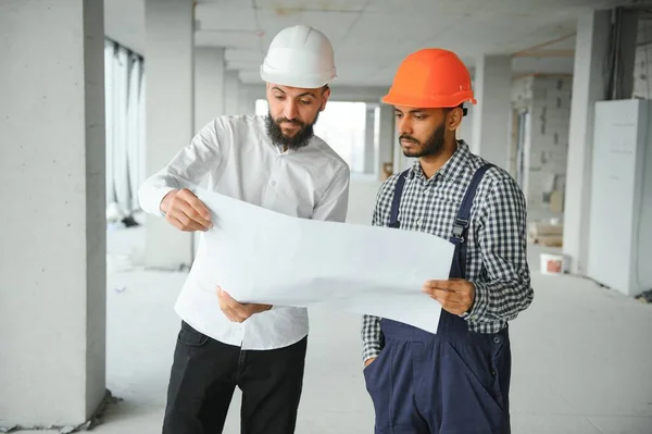 Young attractive arabic industrial engineer in hard hat. Professional and industry, builder architect job, worker checking work at plant indoor.